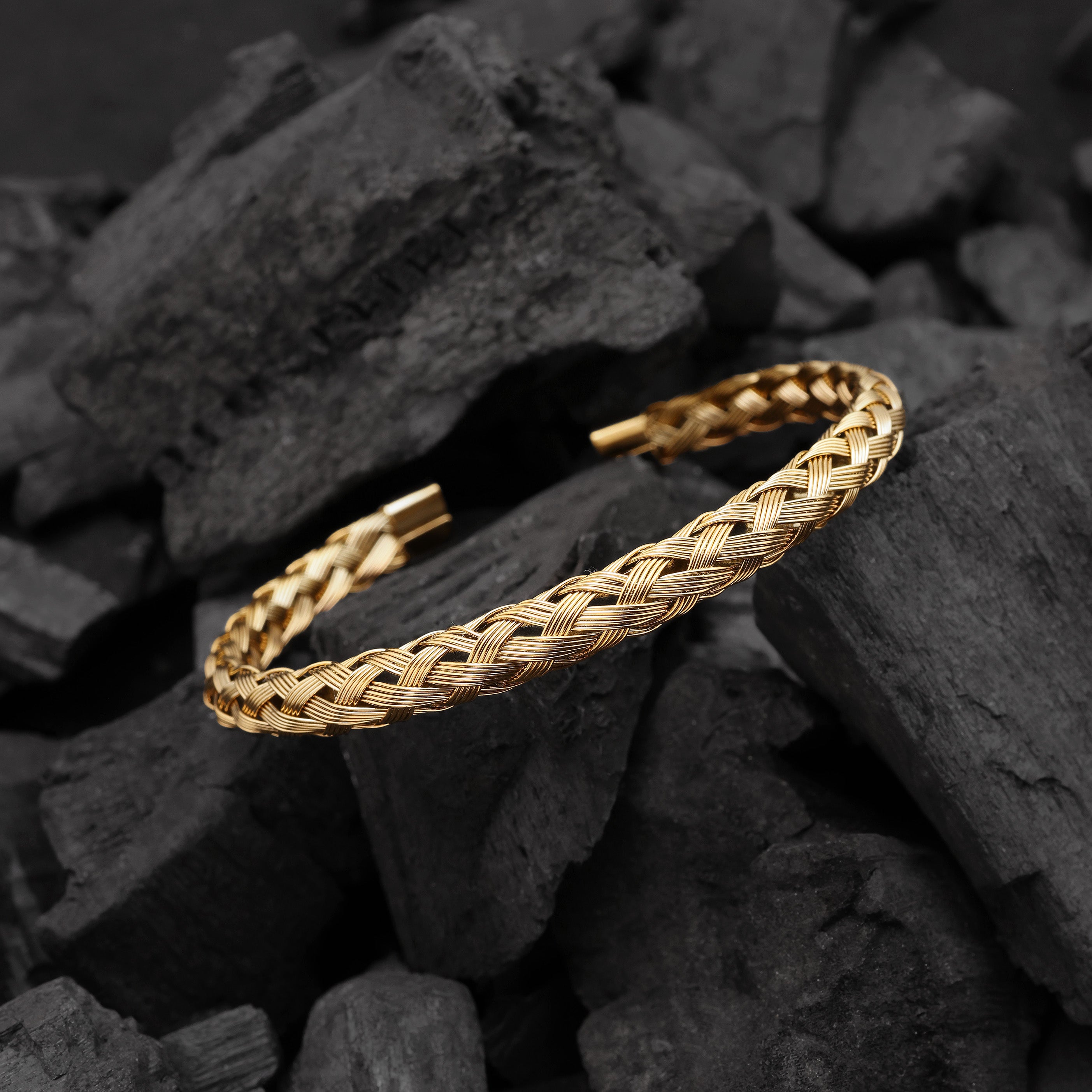 Gold braided bracelet on a dark stone surface
