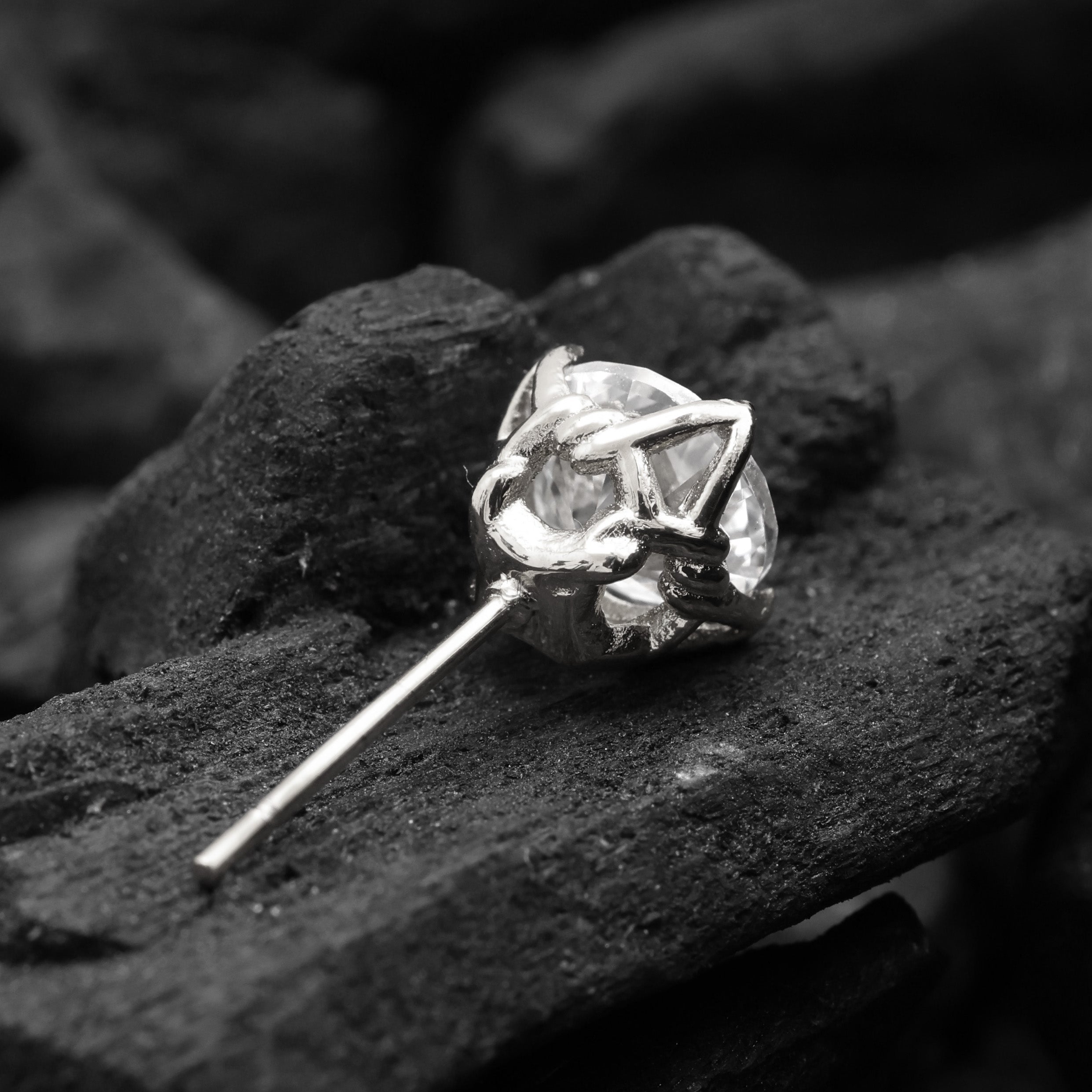 Diamond stud earring on a dark stone surface