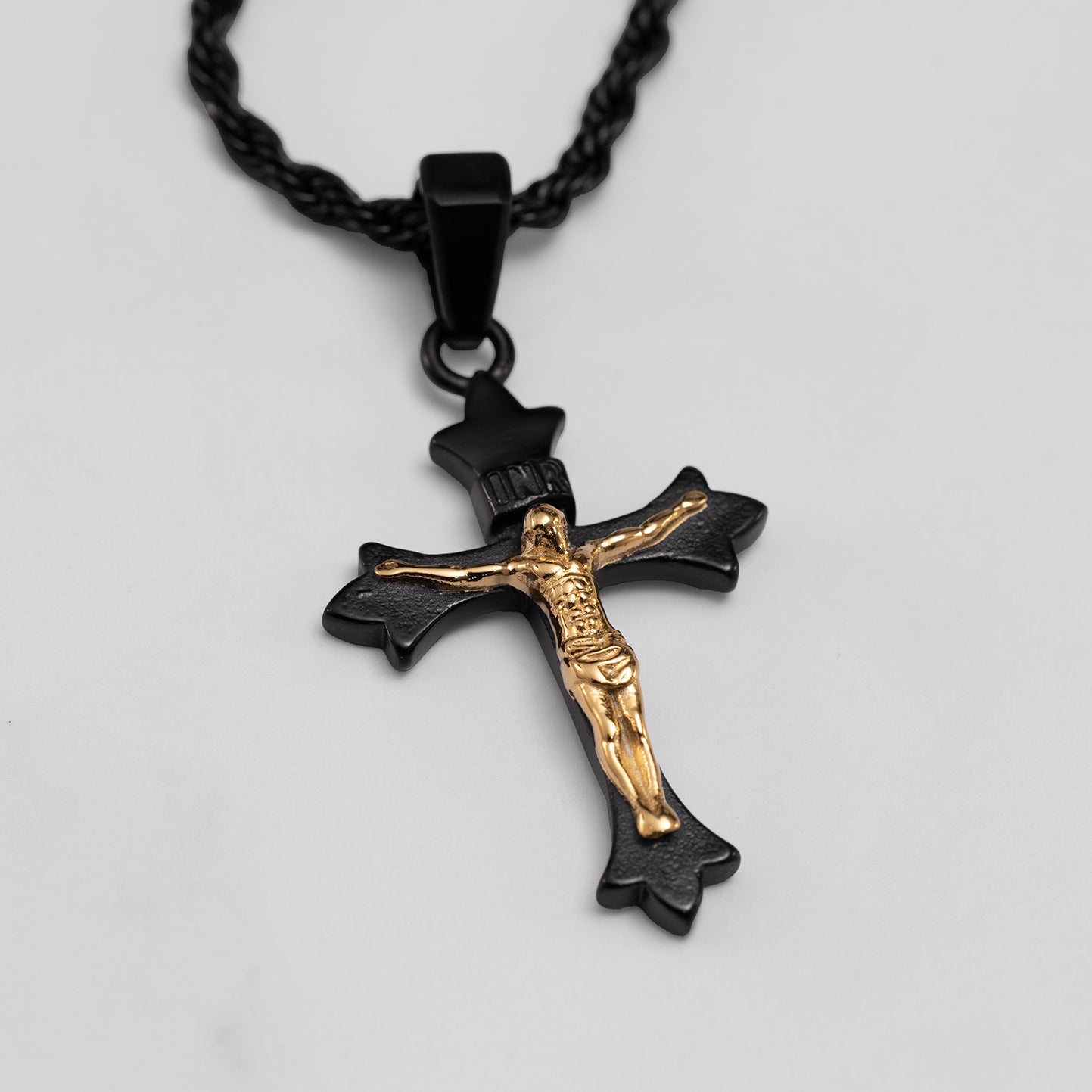 Black and gold crucifix pendant on a gray background