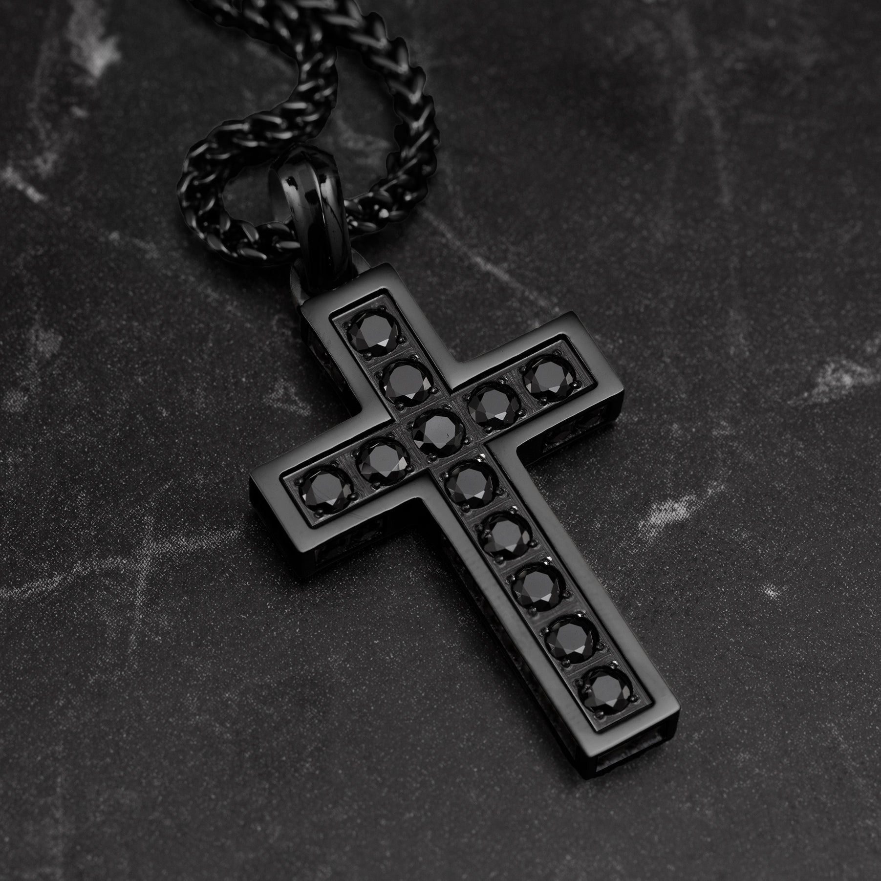 Black cross pendant necklace on a dark textured background