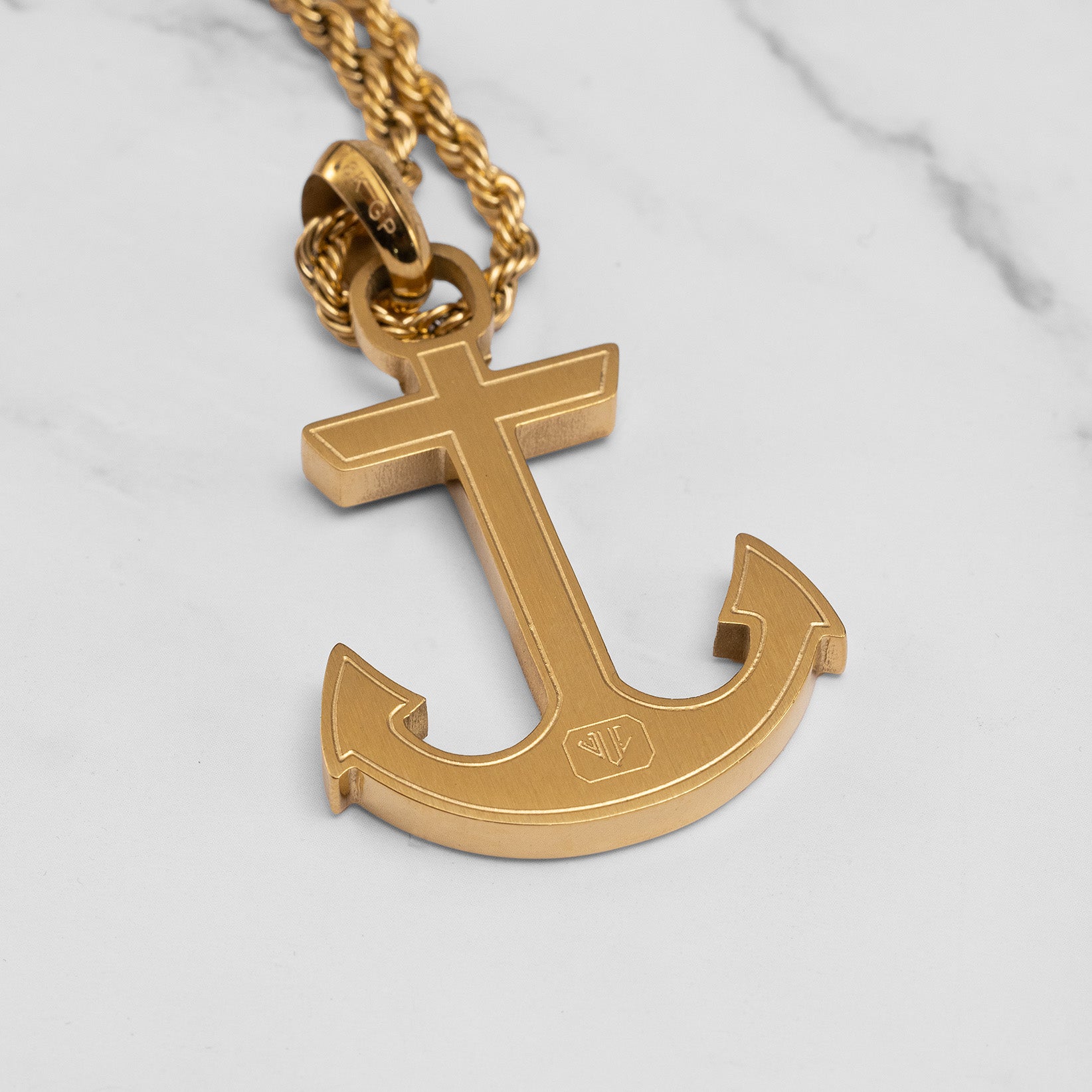 Gold anchor pendant on a chain against a light gray background