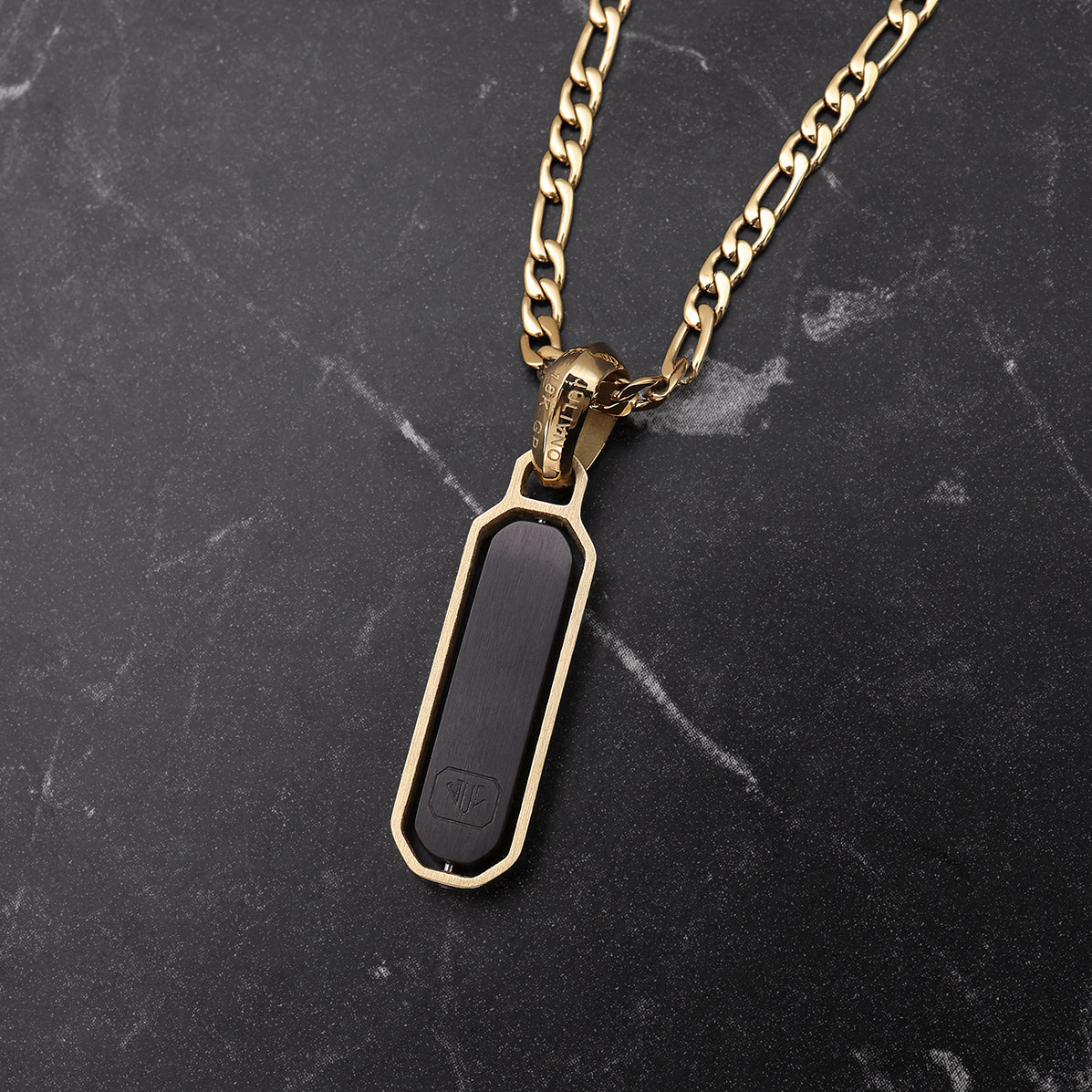 Gold necklace with a black pendant on a dark marble surface