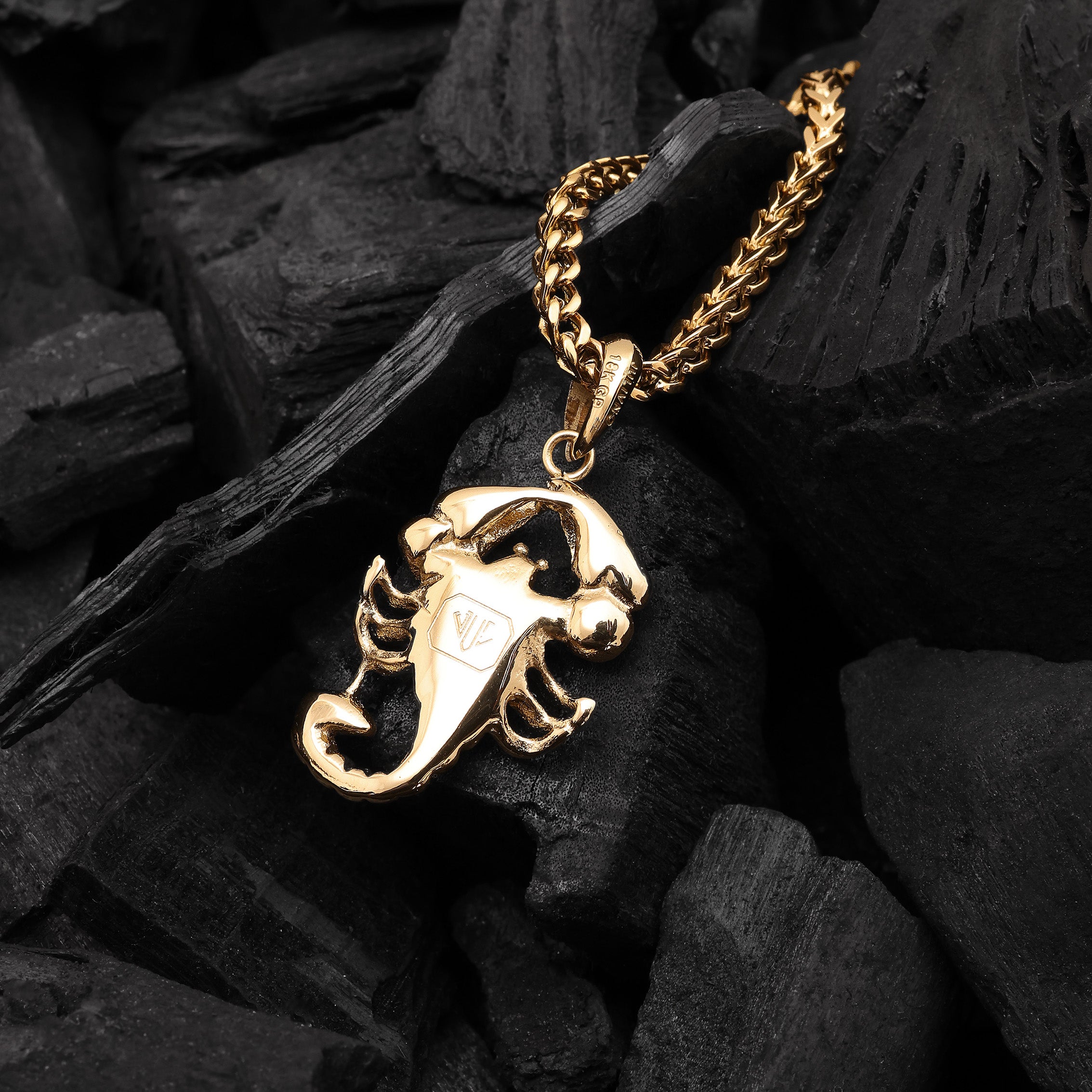Gold scorpion pendant necklace on a dark stone background