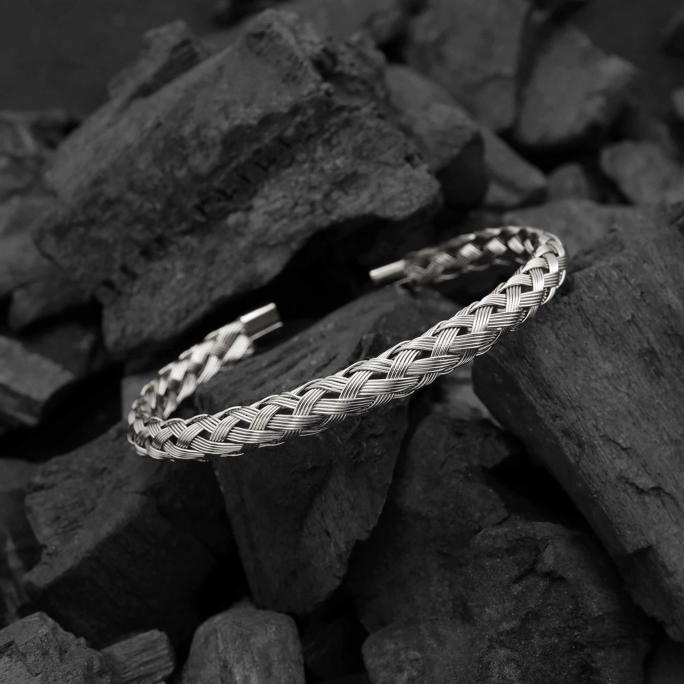 Silver braided bracelet on a dark stone surface