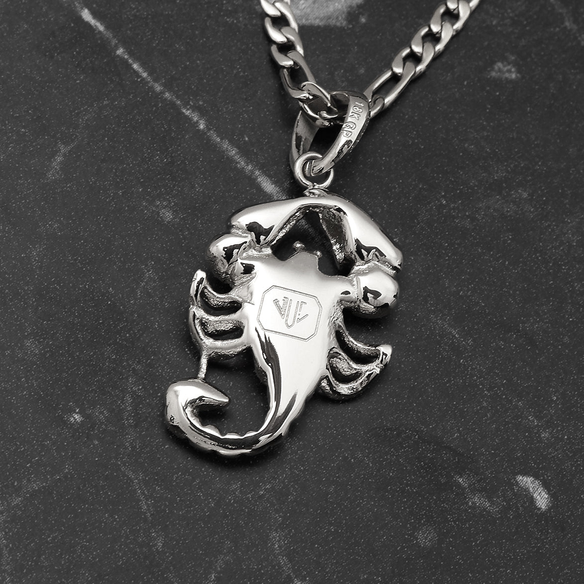 Silver scorpion pendant on a chain against a dark background