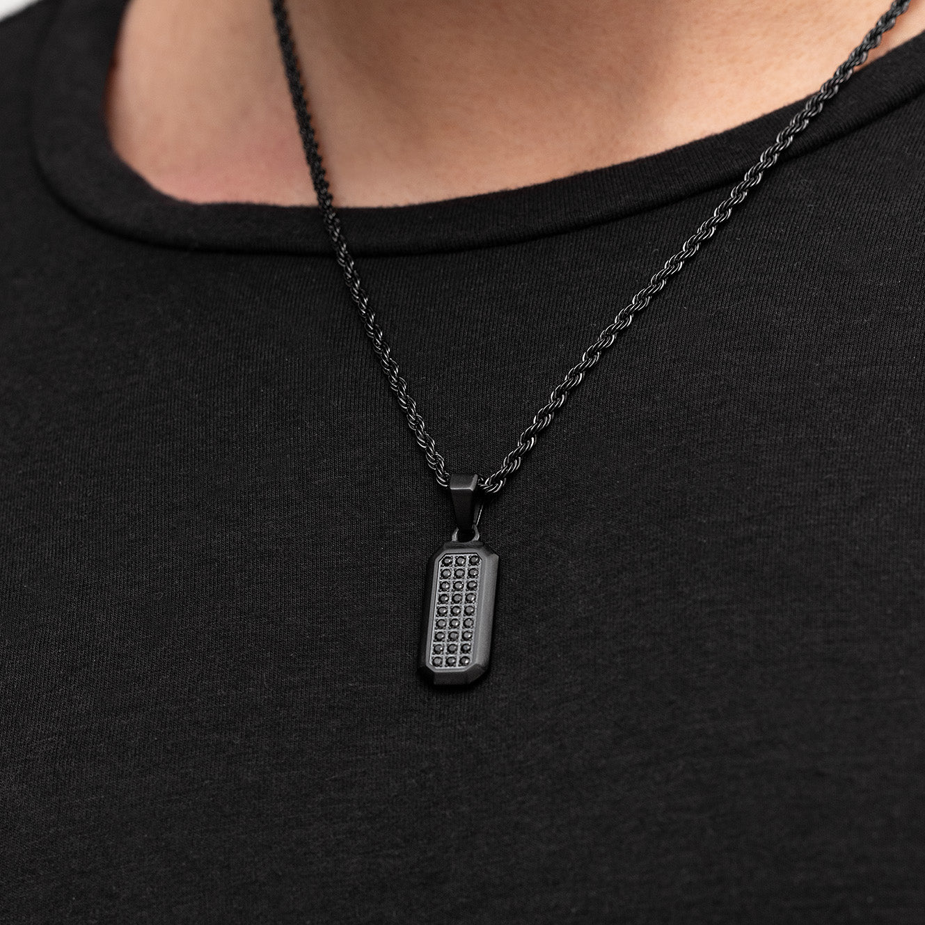 Black necklace with a rectangular pendant on a black shirt