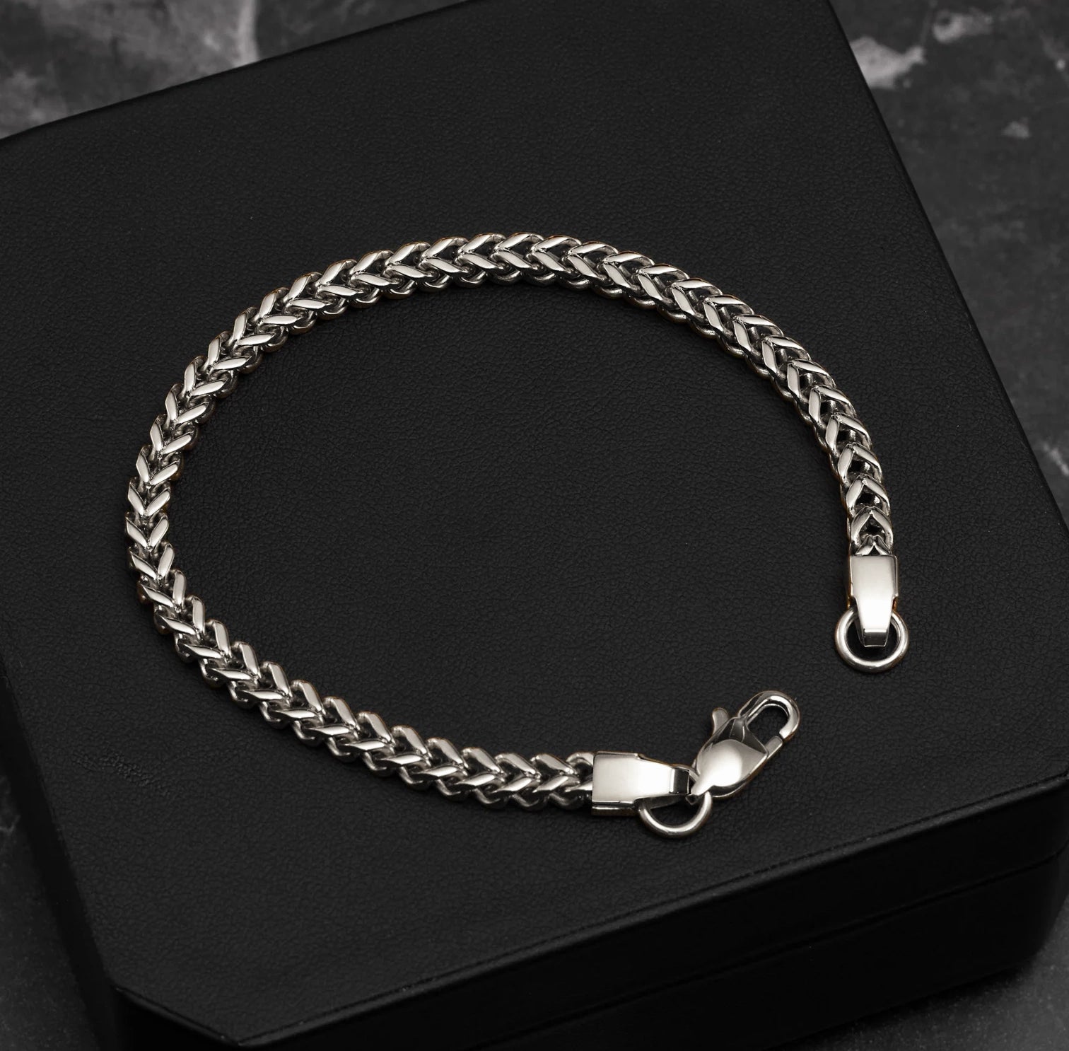 Silver chain bracelet on a black surface