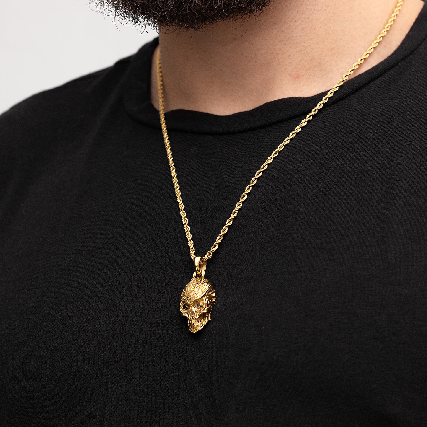 Gold necklace with a pendant on a black shirt against a light gray background